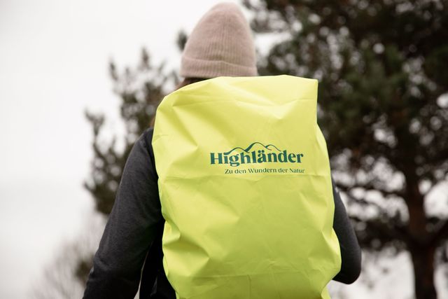 Das Regencover in der Corporate Colour stärkt das Outdoor-Branding. Gedrucktes Logo auf einem Neongelben Rucksack-Regencover.